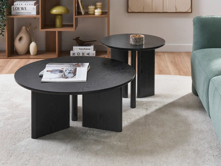 Modern living room with black coffee table and side table, green sofa, and decorative items.