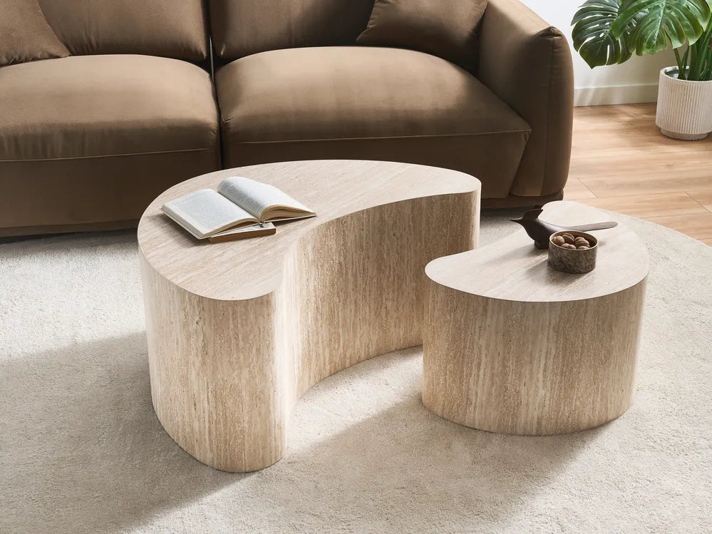 A modern curved wooden coffee table with a matching smaller side table in a living room setting, positioned in front of a brown sofa on a light beige rug.