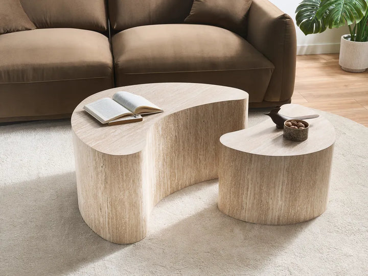 A modern curved wooden coffee table with a matching smaller side table in a living room setting, positioned in front of a brown sofa on a light beige rug.