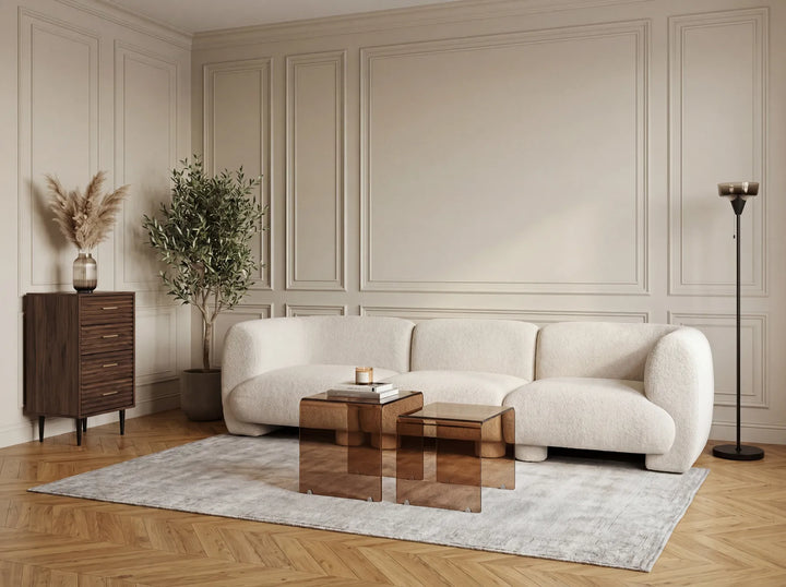 Modern living room with a beige sofa, glass coffee table, and decorative elements.