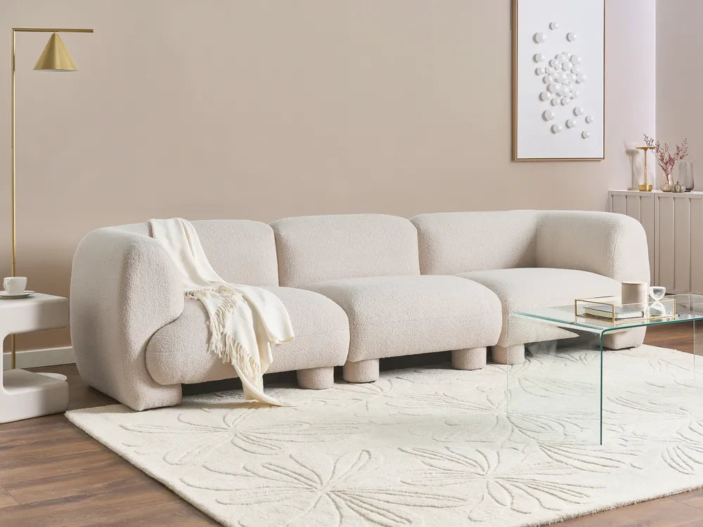 Modern living room with a beige sofa, glass coffee table, and decorative elements.