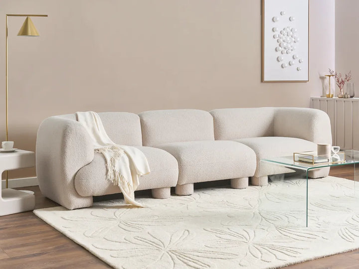 Modern living room with a beige sofa, glass coffee table, and decorative elements.