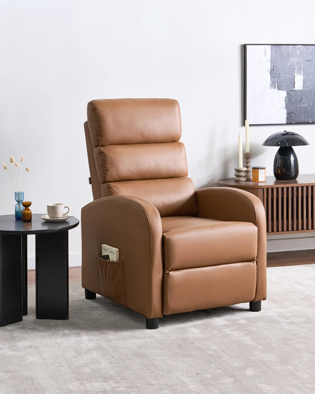 Brown leather recliner chair in a living room setting with a side table and decor items.