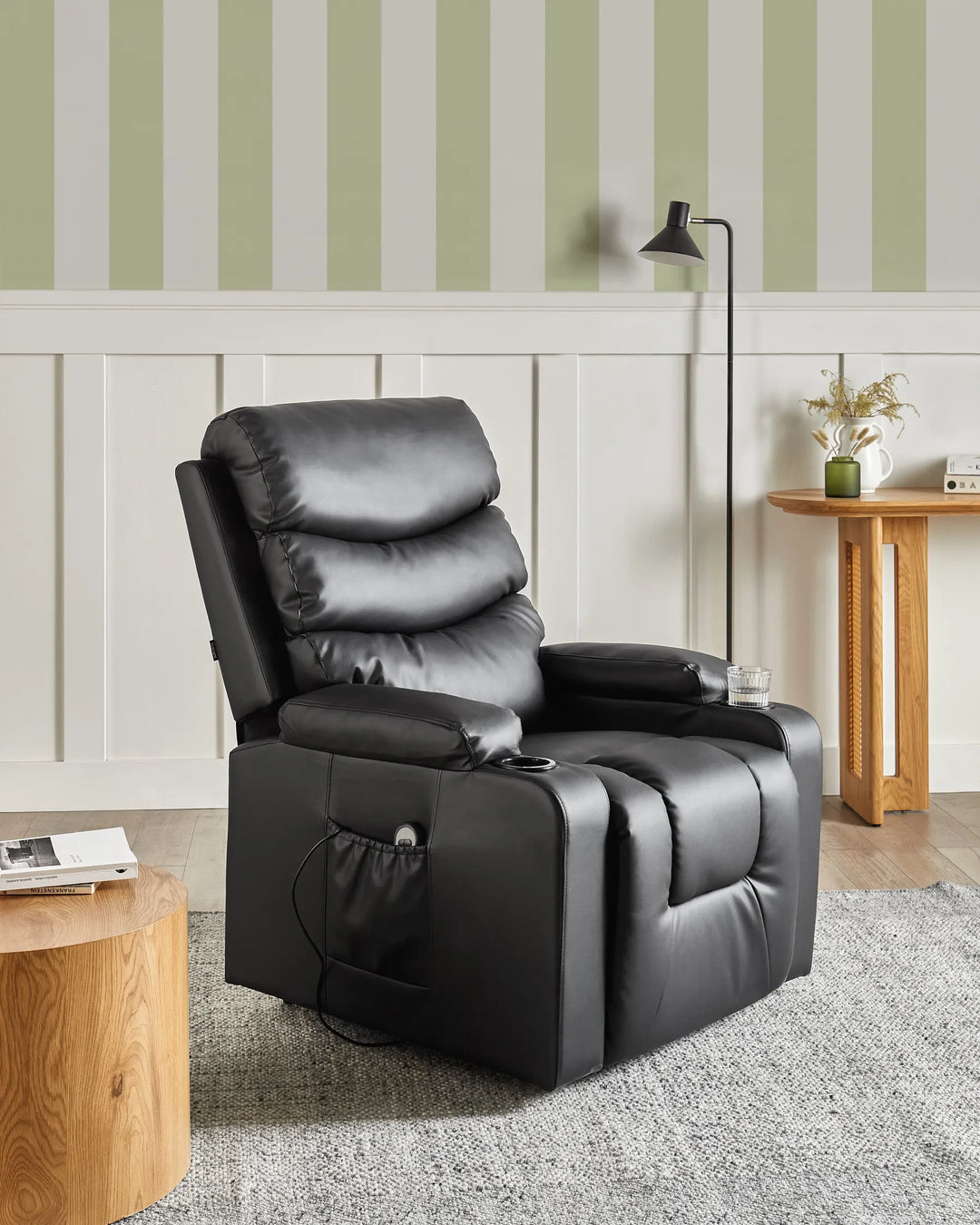 Black recliner chair in a living room with striped wallpaper and wooden furniture.