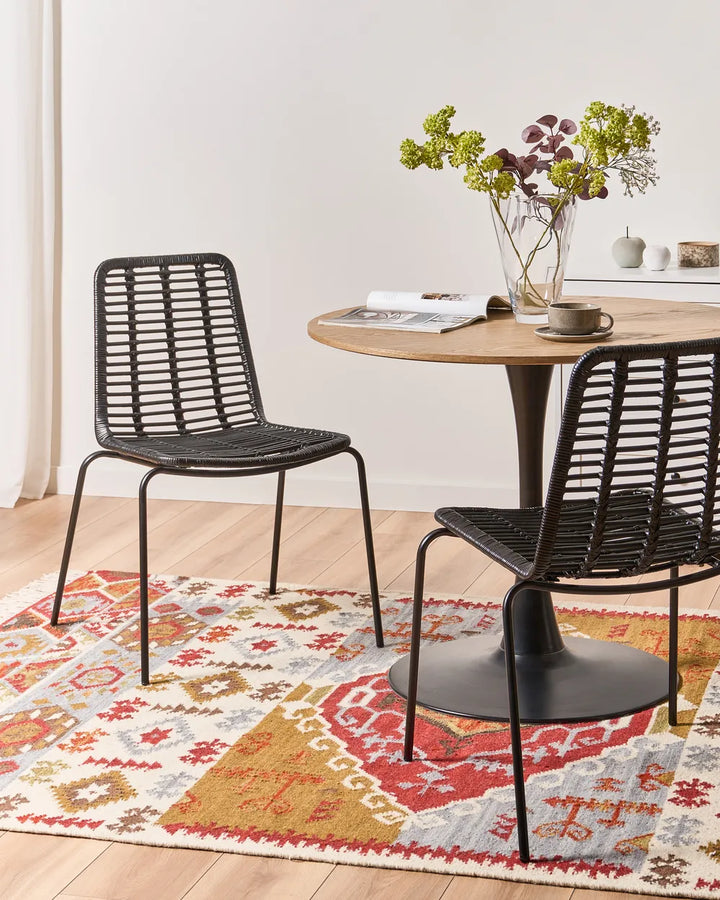 Two black metal dining chairs with woven slatted backs and seats.