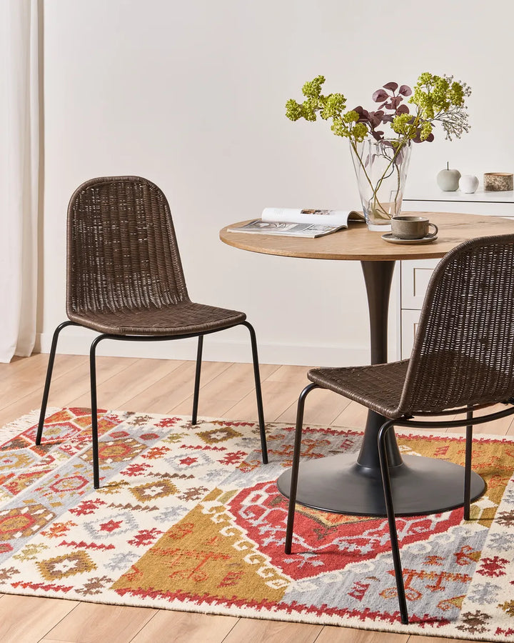 Dining table with two wicker chairs on a patterned rug
