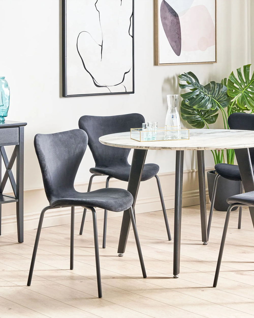 Dining room with round table and gray chairs, light-colored floor, and abstract art on the wall.