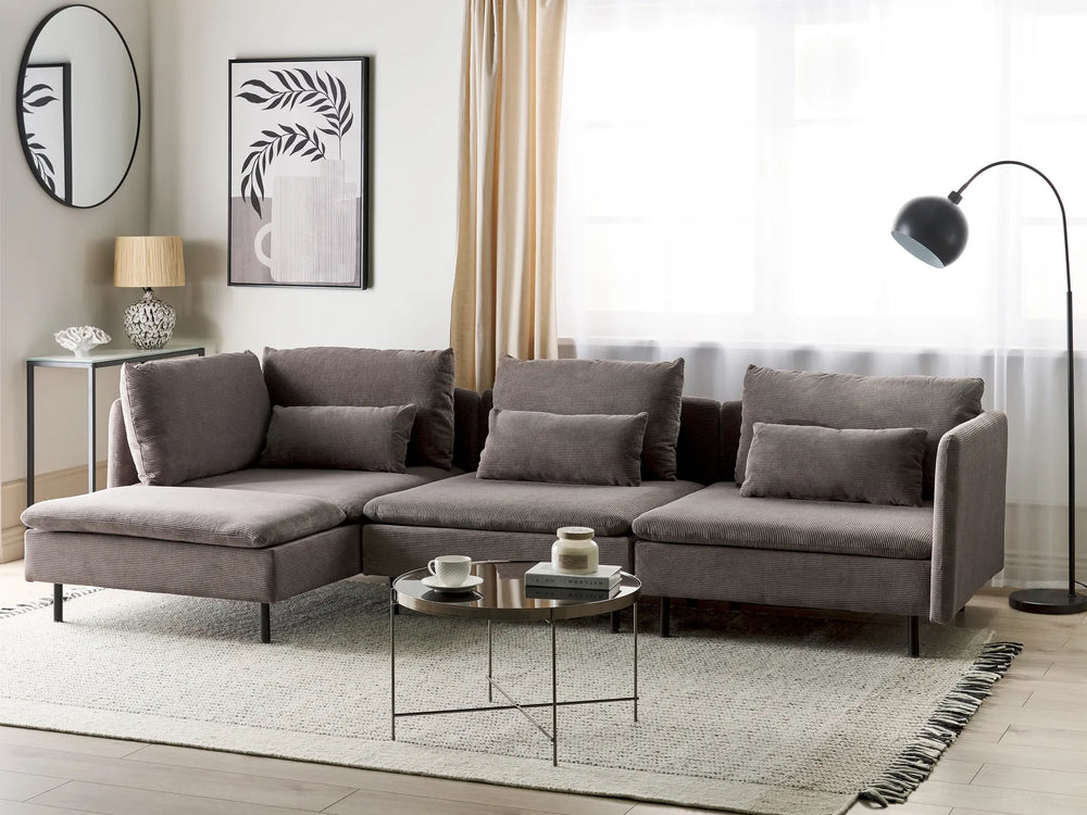 A modern L-shaped sectional sofa upholstered in textured gray fabric, styled in a bright, contemporary living room with a matching gray area rug, a small round coffee table, and a black floor lamp.