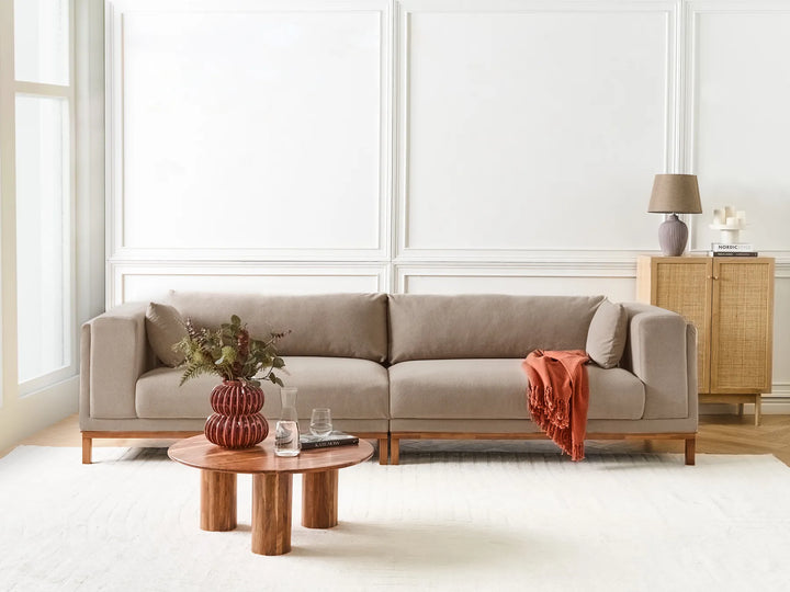 Beige sectional sofa in a modern living room with a wooden coffee table and decorative items.