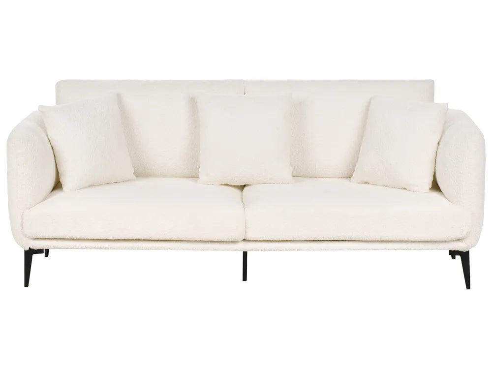 A modern three-seat sofa upholstered in a textured off-white fabric, featuring four matching square throw pillows and slim black metal legs, shown against a plain white background.