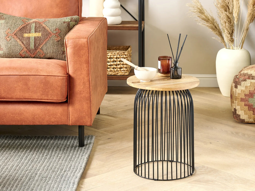 Copper sofa with decorative pillow, wooden side table with candles, and decorative items in a living room setting.