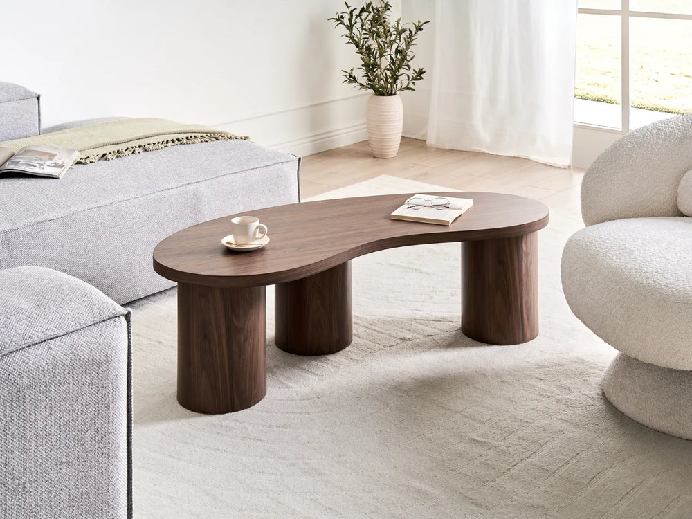 Wooden coffee table in a living room with gray sofa and white curtains.