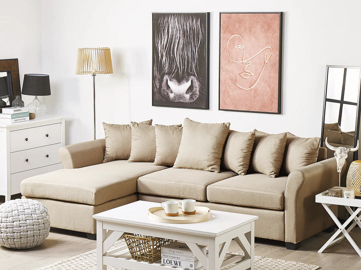 Beige sectional sofa in a living room with decorative items and artwork on the wall.