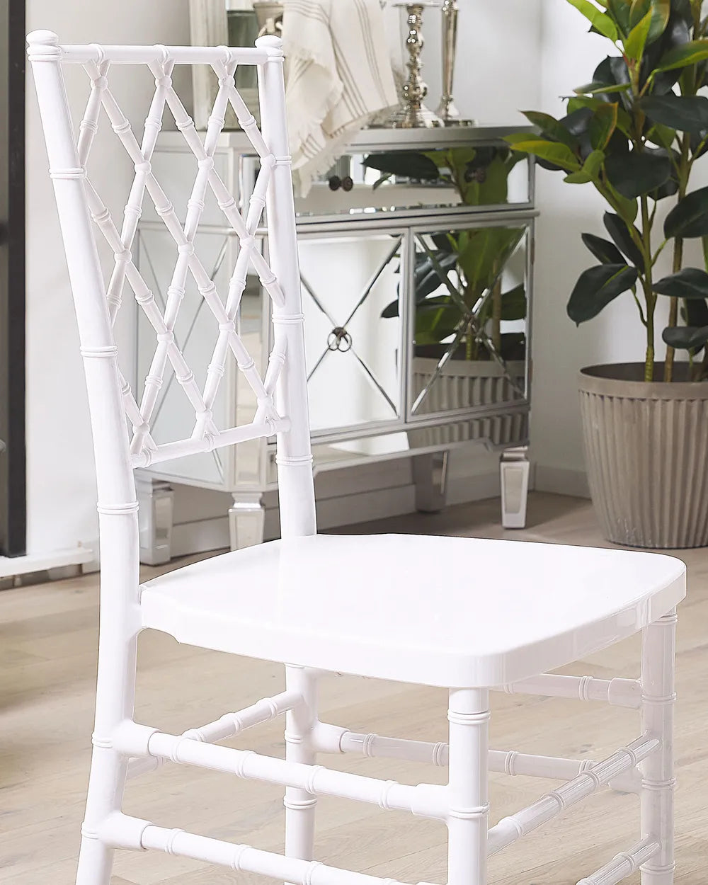 White chair in a room with a mirror and plant