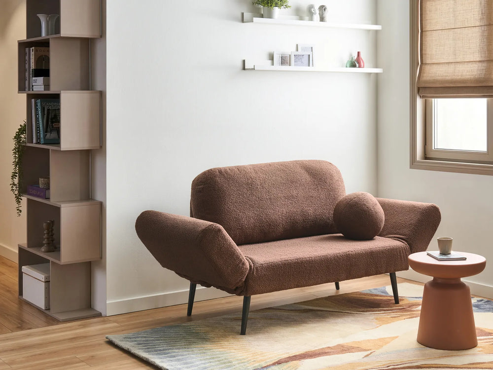 A brown bouclé loveseat sofa with dark metal legs in a modern living room setting, featuring a matching round throw pillow, a terracotta side table, and a light wood floor.