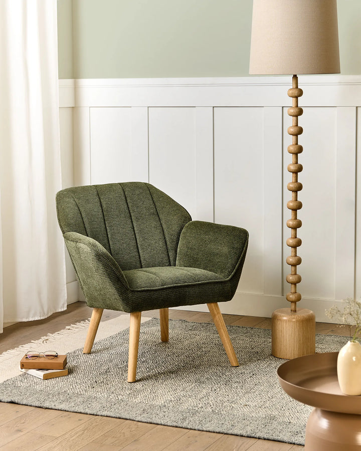 Green armchair in a room with a lamp and decor items.
