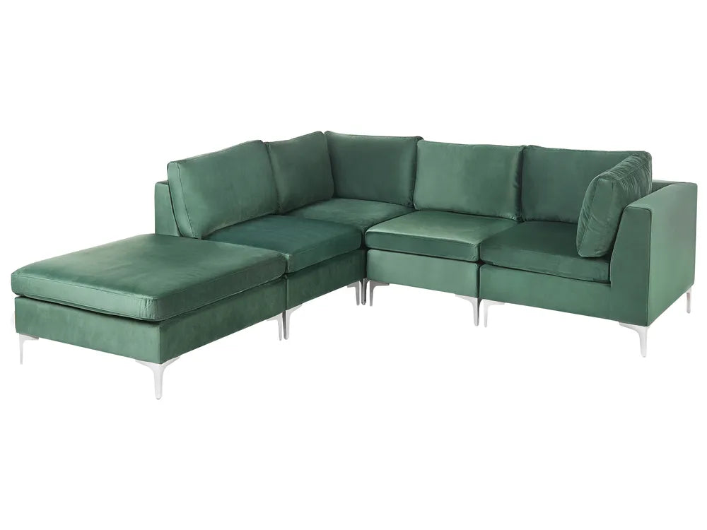 A modern L-shaped sectional sofa upholstered in deep green velvet, featuring a chaise lounge on the left side and slim silver metal legs, shown against a plain white background.