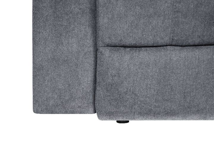 Close-up of a gray upholstered furniture corner showing the fabric texture and seam details against a white background.