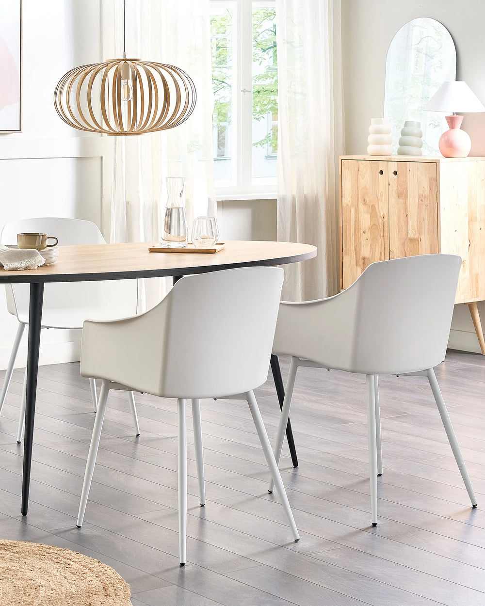 Dining room with a round table and white chairs, wooden floor, and light decor.