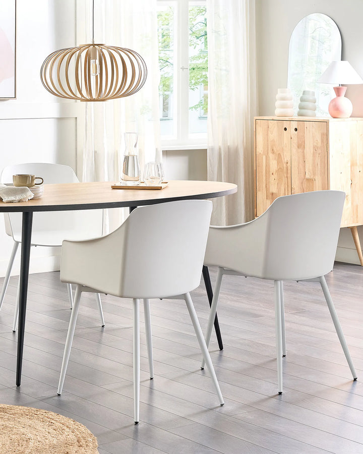 Dining room with a round table and white chairs, wooden floor, and light decor.