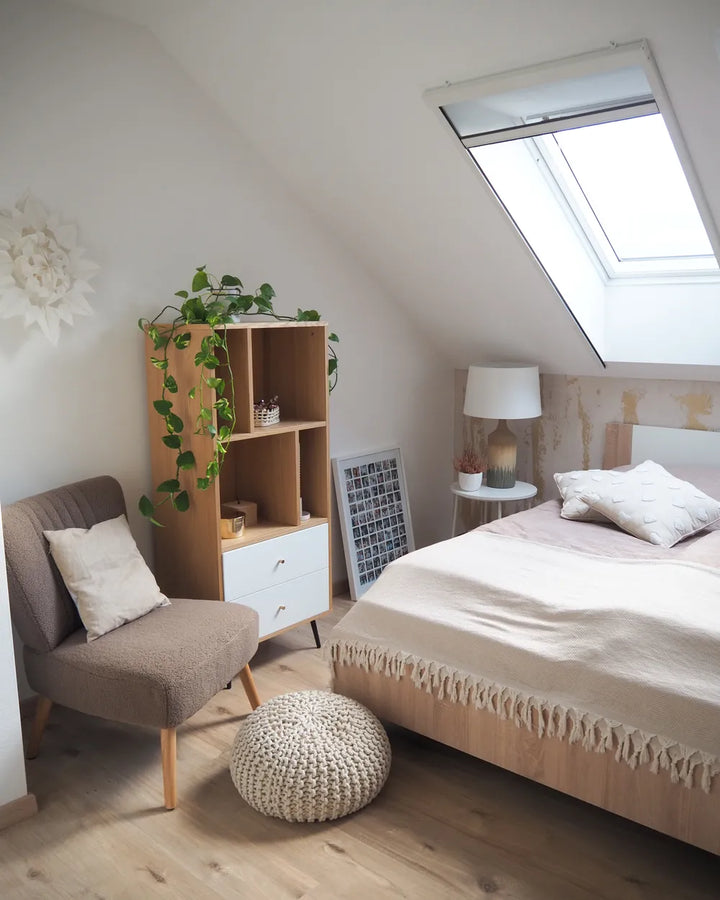 Modern bedroom with a bed, chair, bookshelf, and skylight.