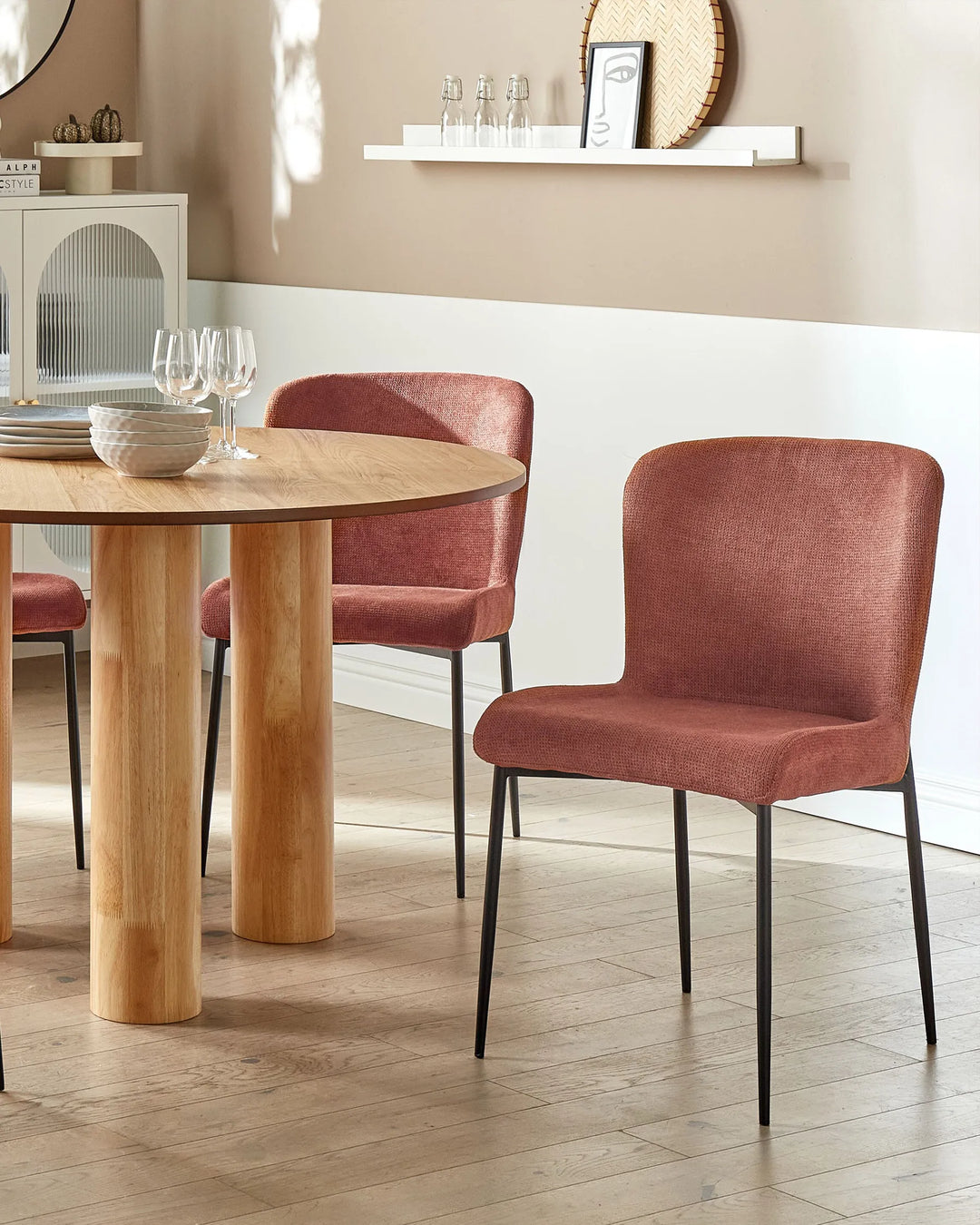 Dining room with wooden table and red chairs against a beige wall.