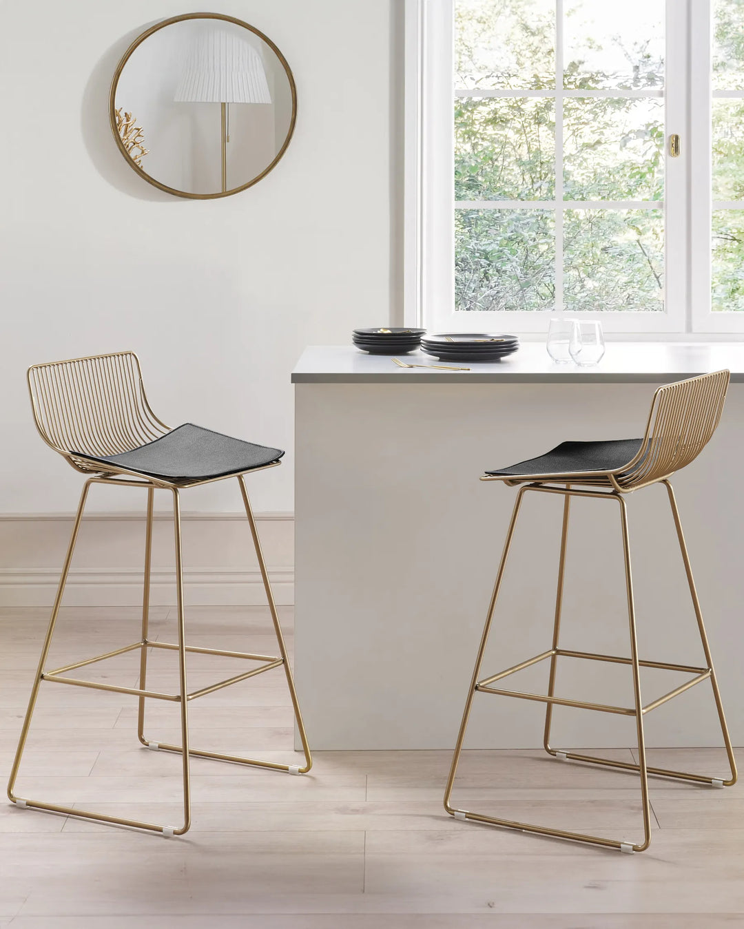 Two modern bar stools with gold frames and black seats in a kitchen setting.