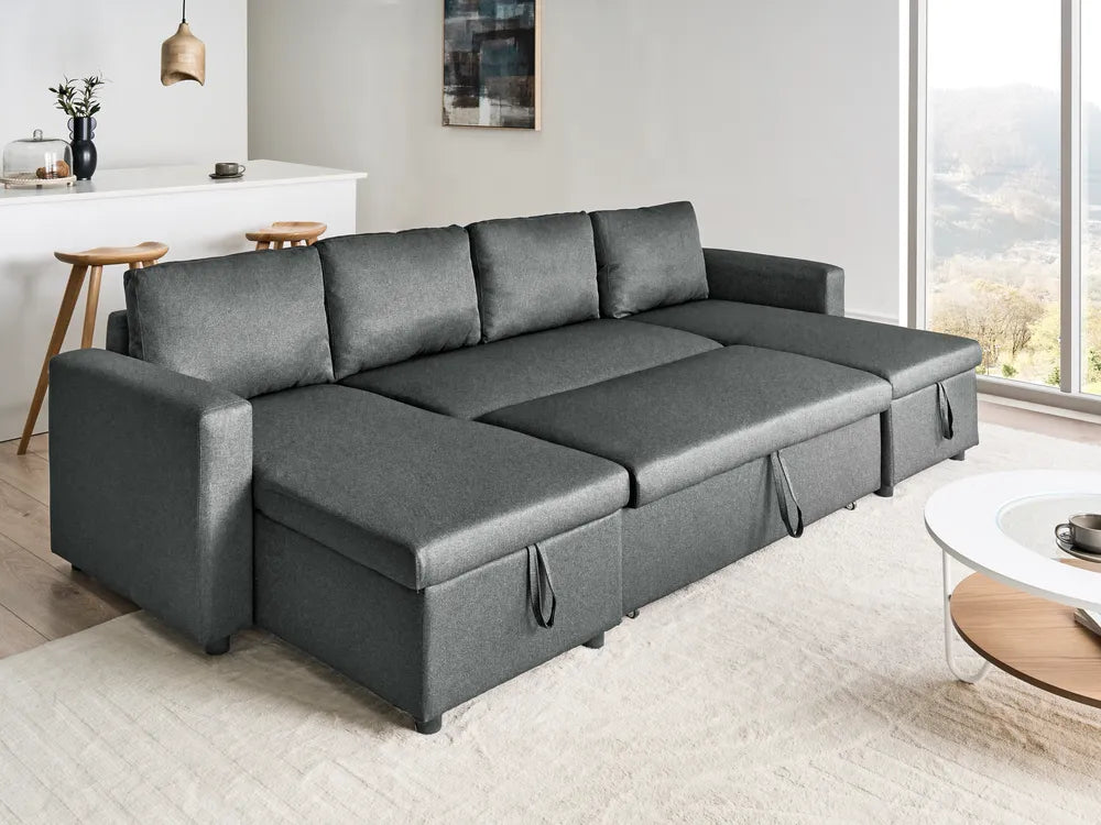 A dark gray fabric sectional sofa with a chaise lounge and storage compartments underneath, shown in a modern living room setting.