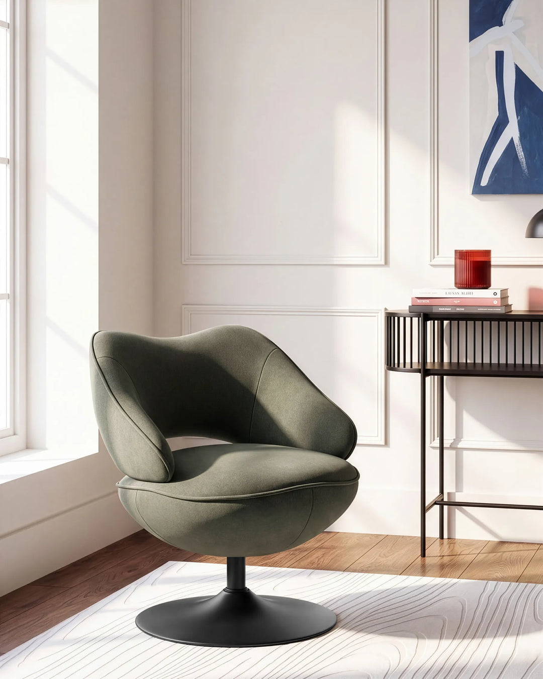 A modern swivel lounge chair in a muted sage green fabric with a black pedestal base, positioned in a bright, contemporary room with white walls, a window, and a side table.