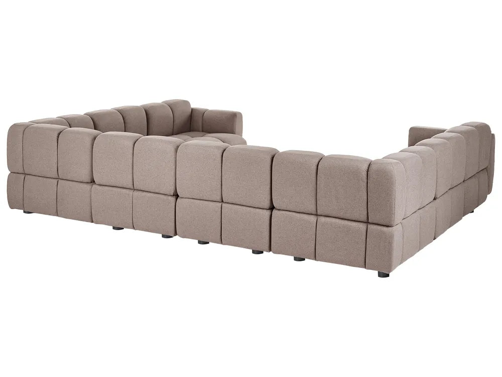 A modular tufted sectional sofa in a taupe beige fabric, shown from a three-quarters angle against a plain white background.