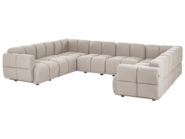 A modular sectional sofa upholstered in a textured taupe fabric, featuring a tufted grid pattern and blocky, modern design, shown on a plain white background.