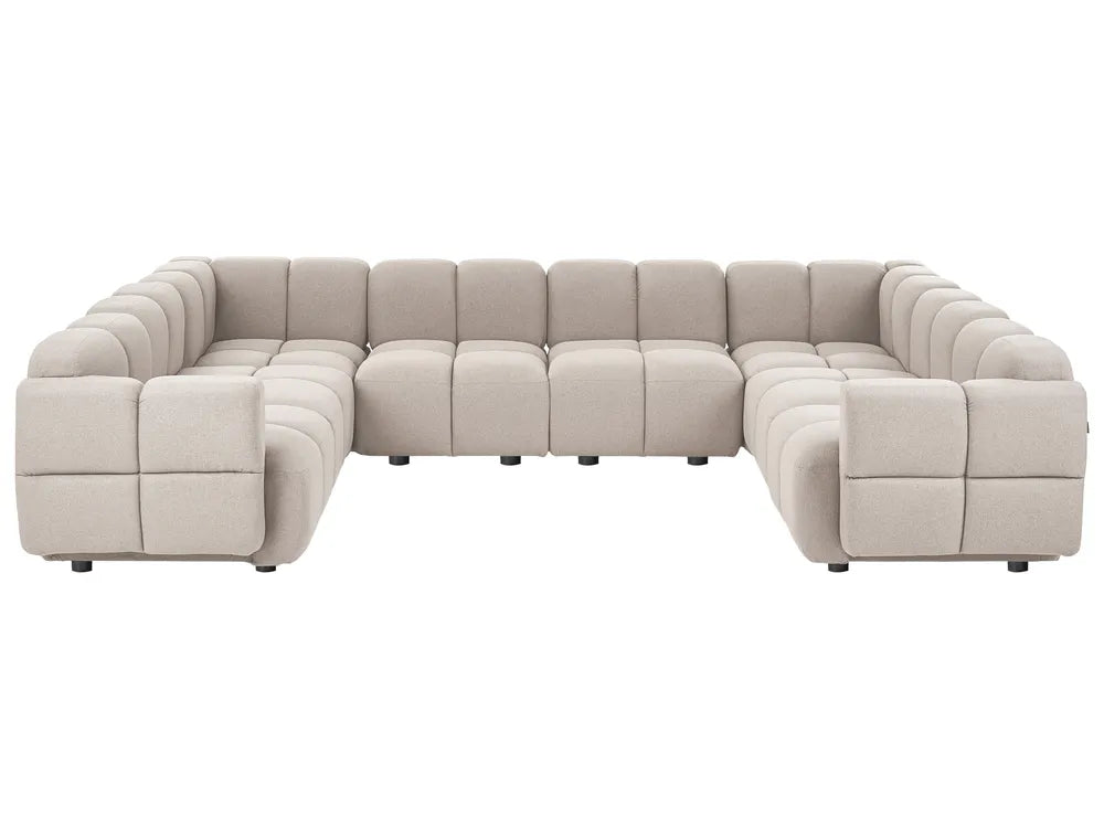 A modular sectional sofa upholstered in a light beige textured fabric, featuring a modern blocky design with deep channel tufting on the backrests and armrests, shown against a plain white background.