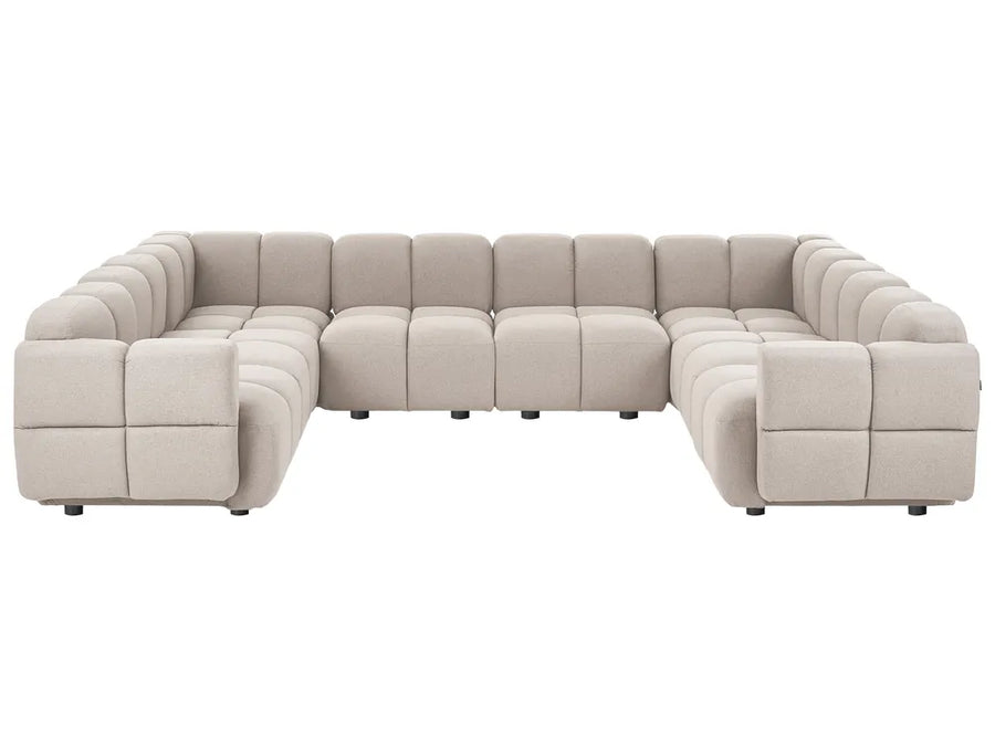 A modular sectional sofa upholstered in a light beige textured fabric, featuring a modern blocky design with deep channel tufting on the backrests and armrests, shown against a plain white background.