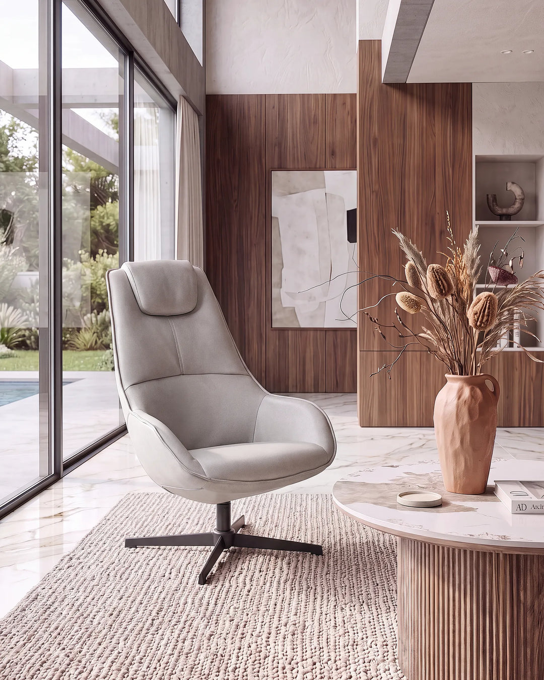 A modern light gray upholstered swivel lounge chair with a black metal star base, placed in a contemporary living room setting with a marble coffee table, dried flowers, and large windows.