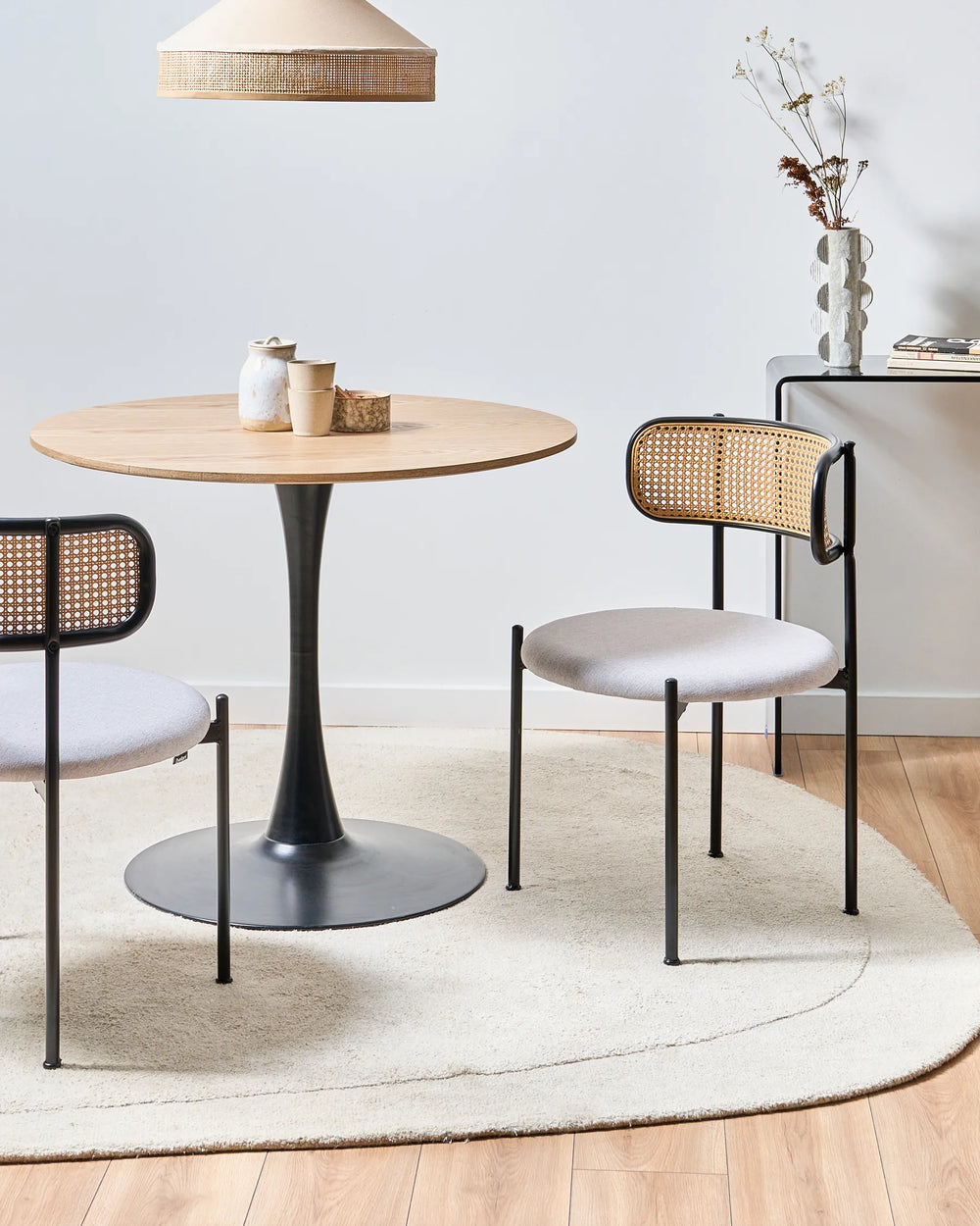 Round wooden table with four chairs in a modern room setting.