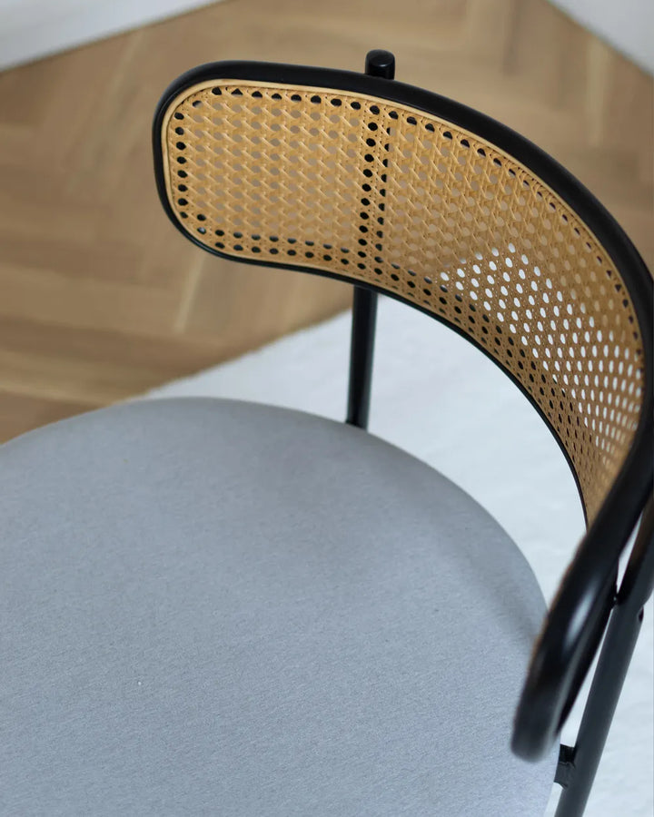 Chair with woven backrest and gray seat on a wooden floor.