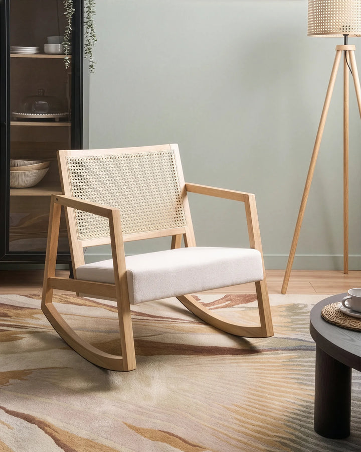 Wooden rocking chair with woven backrest in a room with a lamp and shelves.