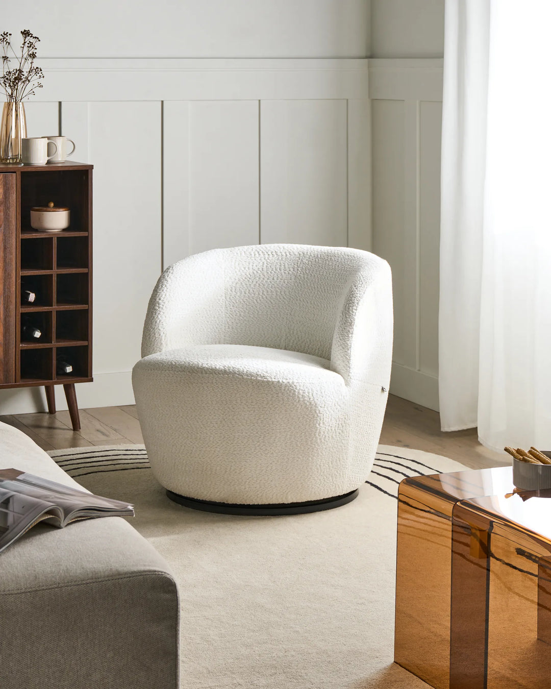 White textured armchair in a modern living room setting with a wooden side table and bookshelf.