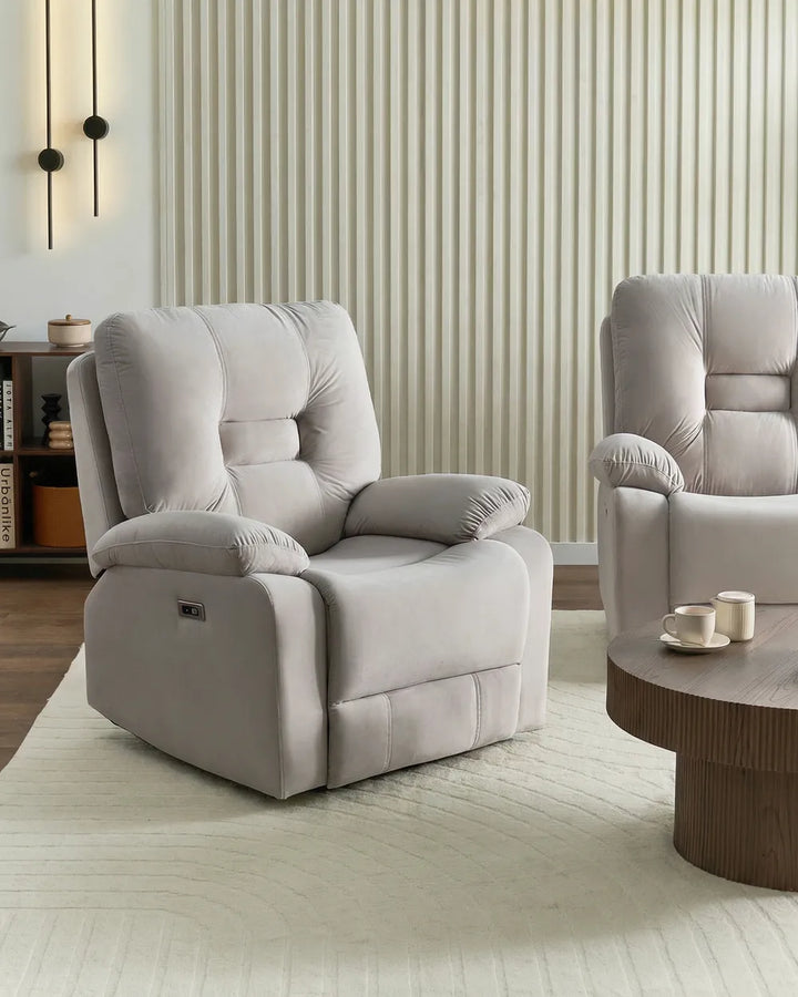 A light gray upholstered recliner chair shown in a modern living room setting with a striped wall, wood floor, and a matching chair partially visible on the right.