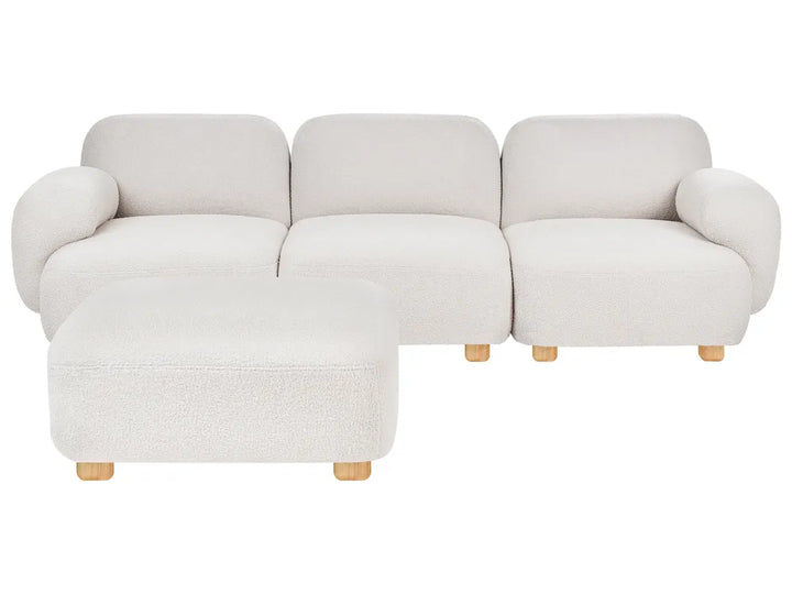 A modern three-seat sofa with a matching ottoman, upholstered in a textured cream bouclé fabric with light natural wood legs, shown against a plain white background.