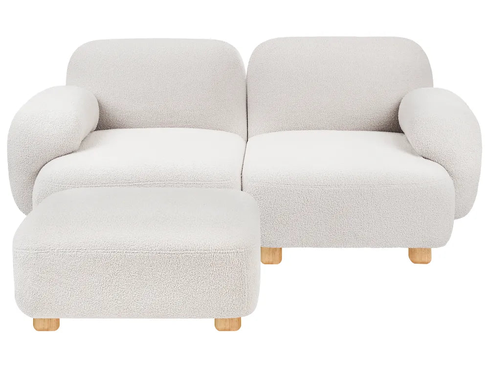 A modern two-seater sofa with a matching ottoman, upholstered in a textured boucle fabric in a light cream color, with small light wood legs.