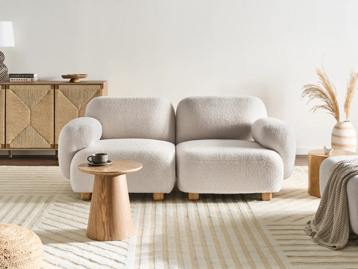 Beige sofa in a modern living room with wooden side table and decorative elements.