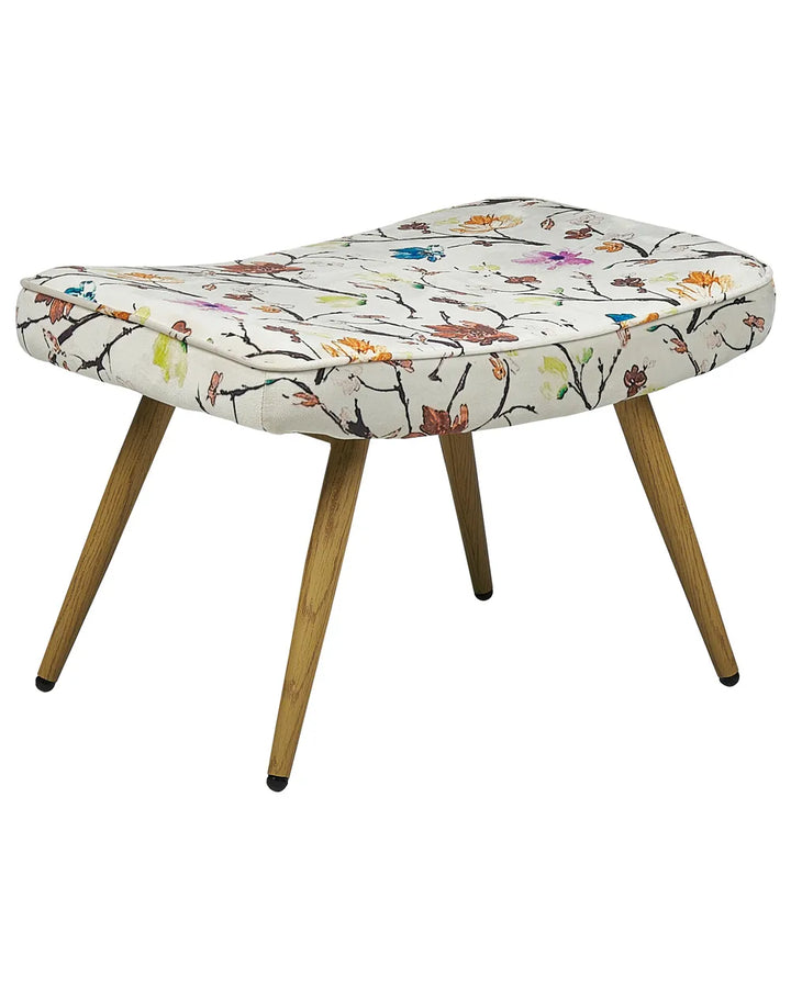 An upholstered bench or ottoman with a cream fabric seat covered in a colorful floral and branch print, supported by four angled wooden legs with black tips, shown on a plain white background.