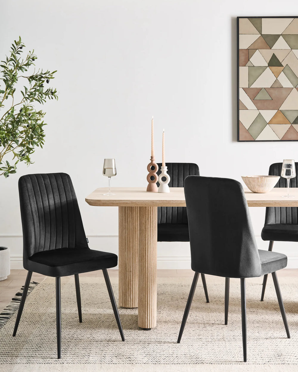 Dining room with a wooden table and black chairs, featuring a geometric wall art piece.