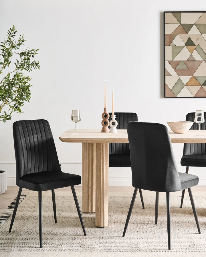 Dining room with a wooden table and black chairs, featuring a geometric wall art piece.