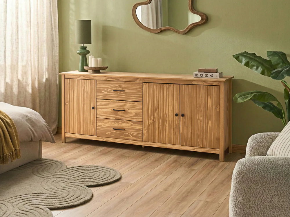 Wooden sideboard in a living room with a green wall and decorative items.