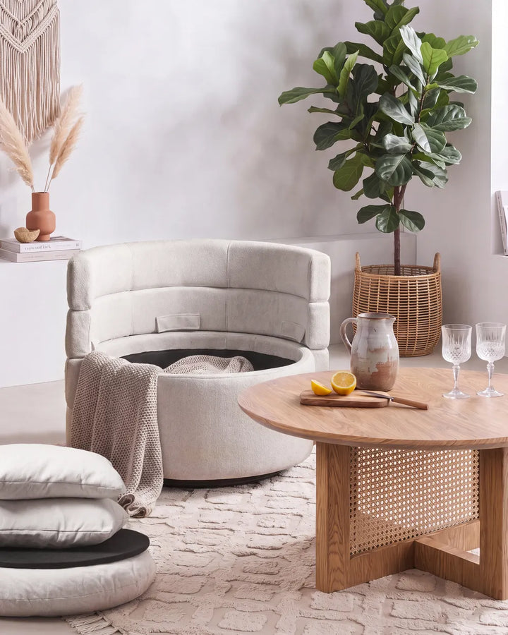 A light beige upholstered accent chair with two back cushions in a bright, modern living room.