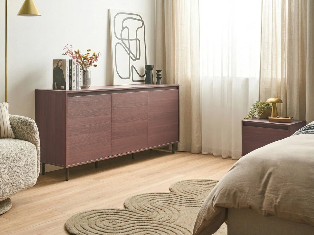 Modern bedroom with wooden sideboard, armchair, and bed.