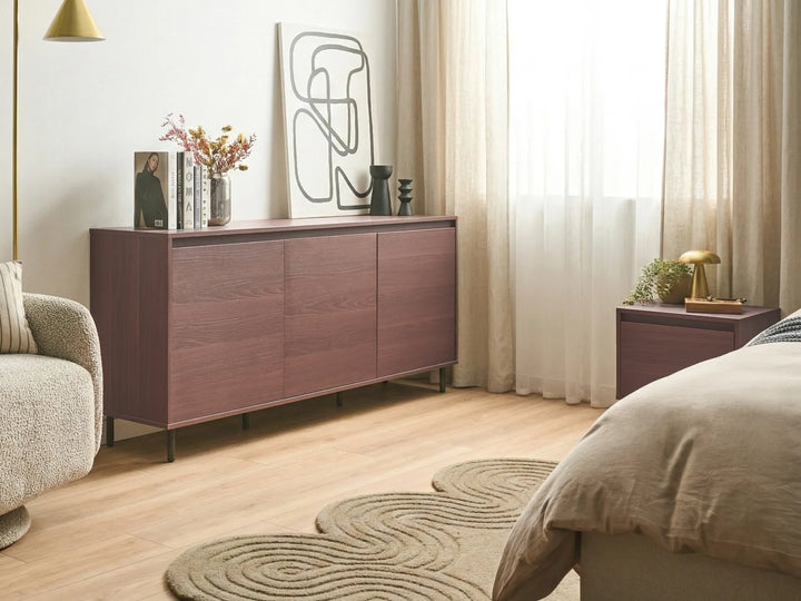 Modern bedroom with wooden sideboard, armchair, and bed.