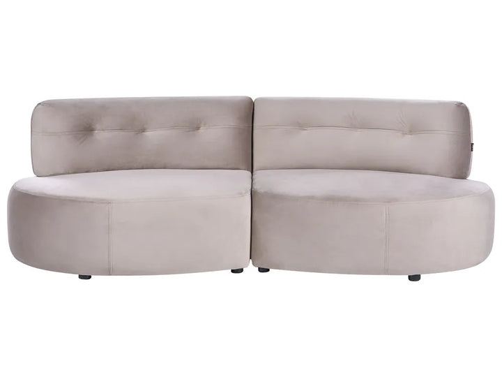 A modern curved modular sofa upholstered in a light taupe-beige velvet fabric, featuring tufted backrests and small black feet, shown against a plain white background.